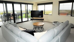 A modern living room with a grey sofa, a coffee table, and a flat-screen TV. - Castle on the Hill, Ocean Grove. (Ocean Grove)