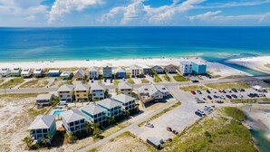 A coastal hotel with multiple buildings, a parking area, and a beach in the background. - Lagoon Views | Beach Access | Pool and Pier Amenities (Gulf Shores)