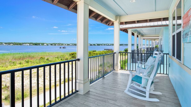 A covered porch with a view of a lake and distant buildings. - Lagoon Views | Beach Access | Pool and Pier Amenities (Gulf Shores)