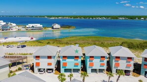A beachfront property with multiple buildings, a sandy beach, and a clear view of the ocean. - Lagoon Views | Beach Access | Pool and Pier Amenities (Gulf Shores)