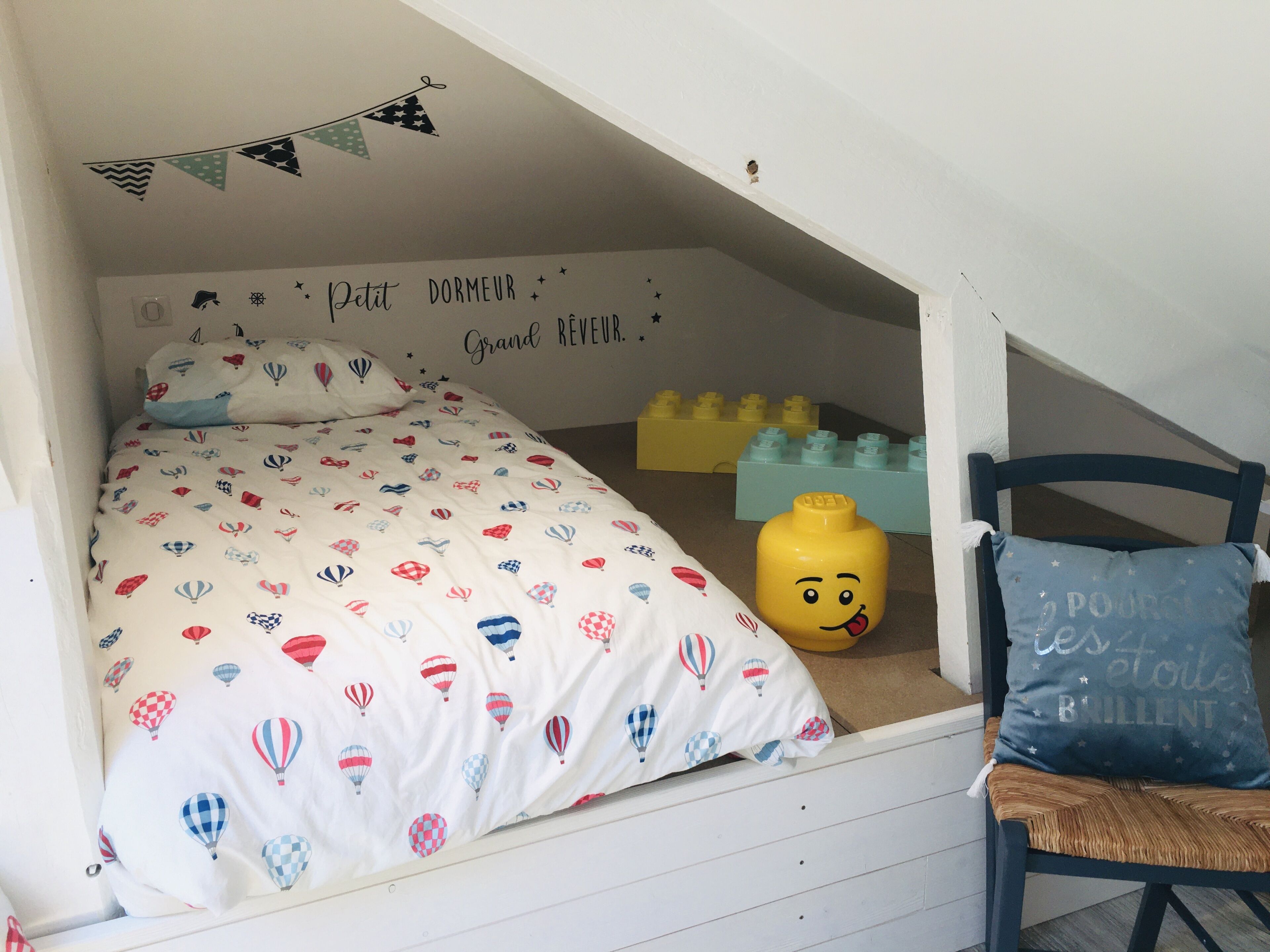 Habitación infantil con cama, almohadas y un juguete.