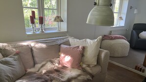 A cozy living room with a sofa, a coffee table, and a lamp. - Urlaub in der Zauberhaft Renovierten Krümelkate (Witzwort)