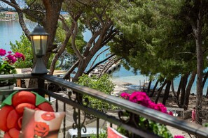 Ein Balkon mit Geländer, der Blick auf einen Strand und ein Gewässer bietet.