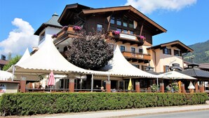 Ein Hotel mit einem großen Balkon, einer Sitzgelegenheit im Freien und einem Schild, das es als Restaurant kennzeichnet.