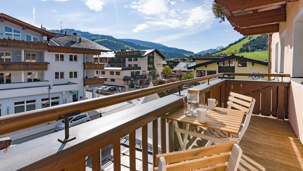 Ein Balkon mit Holzbalkonverkleidung, der auf eine Straße und eine Berglandschaft blickt.