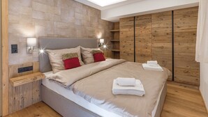 Ein modernes Schlafzimmer mit einem großen Bett, Holzwandverkleidung und eingebauten Regalen.