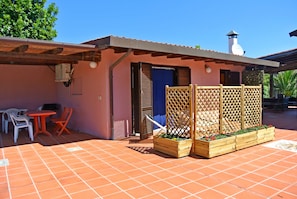 A patio with a table and chairs, a wooden fence, and planters.