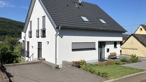 Une maison moderne à deux étages, dotée d’un toit en pente, d’une antenne parabolique et d’un garage.