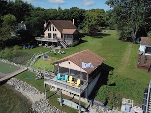 A house with a large deck, a covered area with chairs, and a flag.