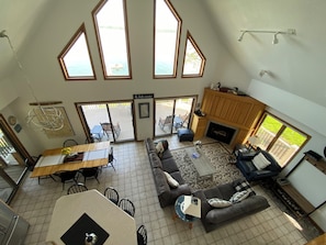 A spacious living area with a large window, a fireplace, and a dining area with a table and chairs.