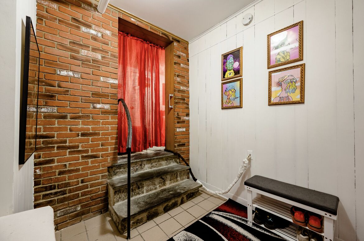Un escalier avec un rideau rouge, un banc et un porte-chaussures.