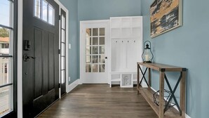 A hallway with a dark door, a white door with glass panels, and a wooden console table with a lantern. - Pool, Hot Tub, Walk to Ice Plant, Smart TVs, BBQ (St. Augustine)