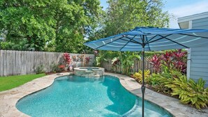 A backyard with a swimming pool, a hot tub, and a patio umbrella. - Pool, Hot Tub, Walk to Ice Plant, Smart TVs, BBQ (St. Augustine)