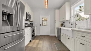 A modern kitchen with stainless steel appliances, white cabinetry, and a wooden floor. - Pool, Hot Tub, Walk to Ice Plant, Smart TVs, BBQ (St. Augustine)