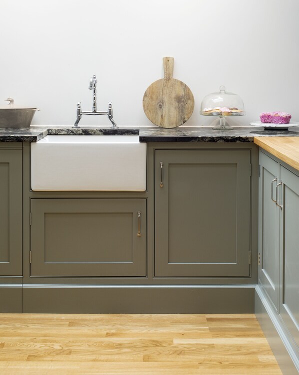 A kitchen with a sink, cabinets, and a wooden countertop.