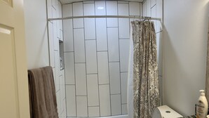 Ein Badezimmer mit Dusche, Toilette und einer Marmorarbeitsplatte.