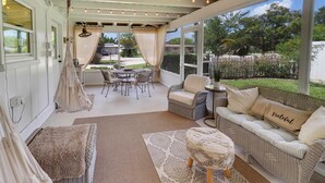 A covered patio with wicker furniture, a cushioned bench, and a patterned rug. - One-of-a-Kind Home! Pet Friendly, Fenced, Private Pool! 1 mi to Downtown & Beach (Venice)
