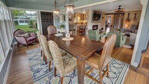 A spacious dining area with a wooden table and chairs, a chandelier, and a view of the outdoors. - One-of-a-Kind Home! Pet Friendly, Fenced, Private Pool! 1 mi to Downtown & Beach (Venice)