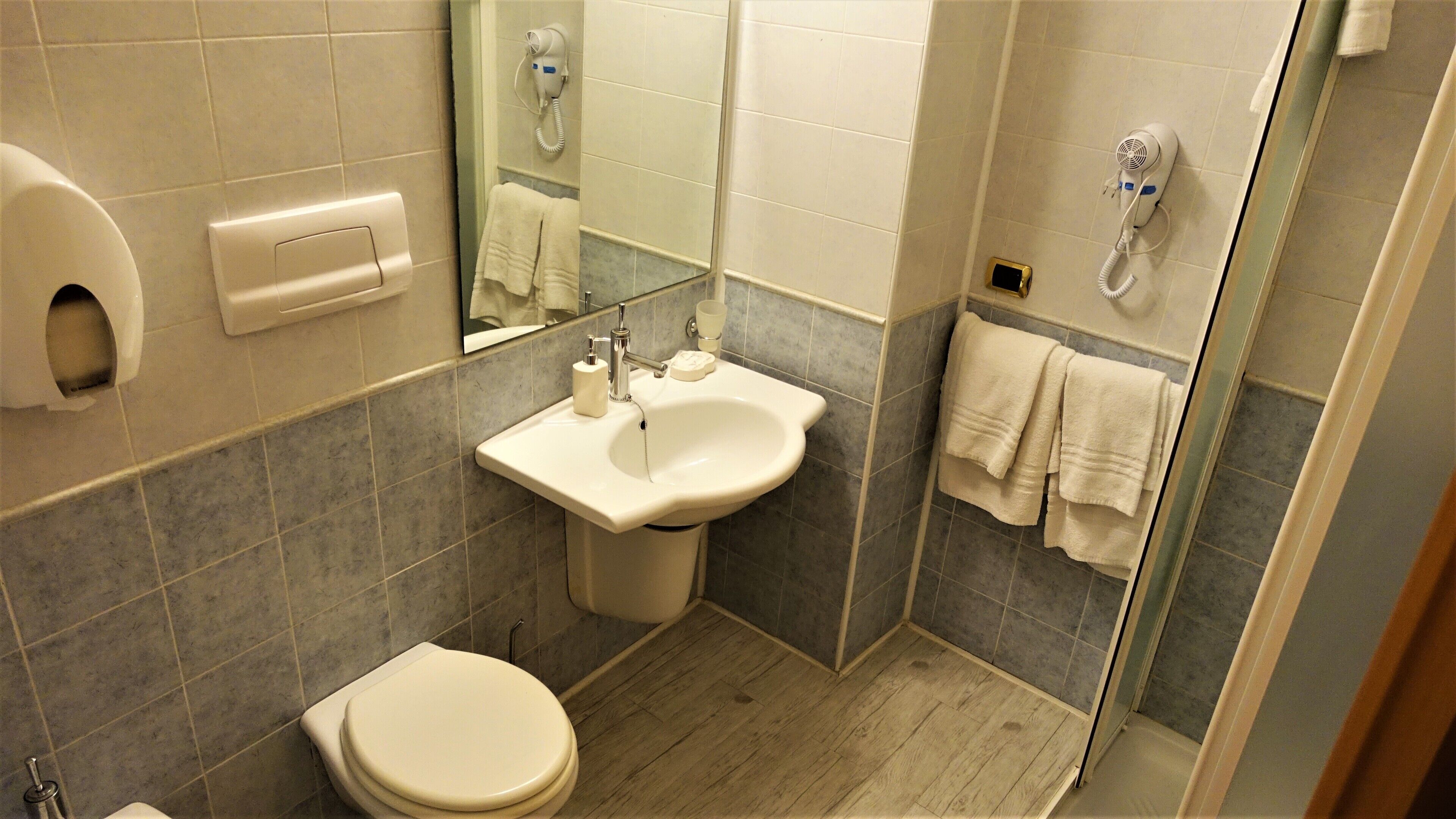 Un baño moderno con inodoro, lavamanos y secamanos.
