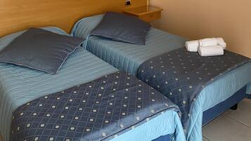Ein Hotelzimmer mit zwei Betten, einem Nachttisch, einer Wandlampe und einem gerahmten Bild.