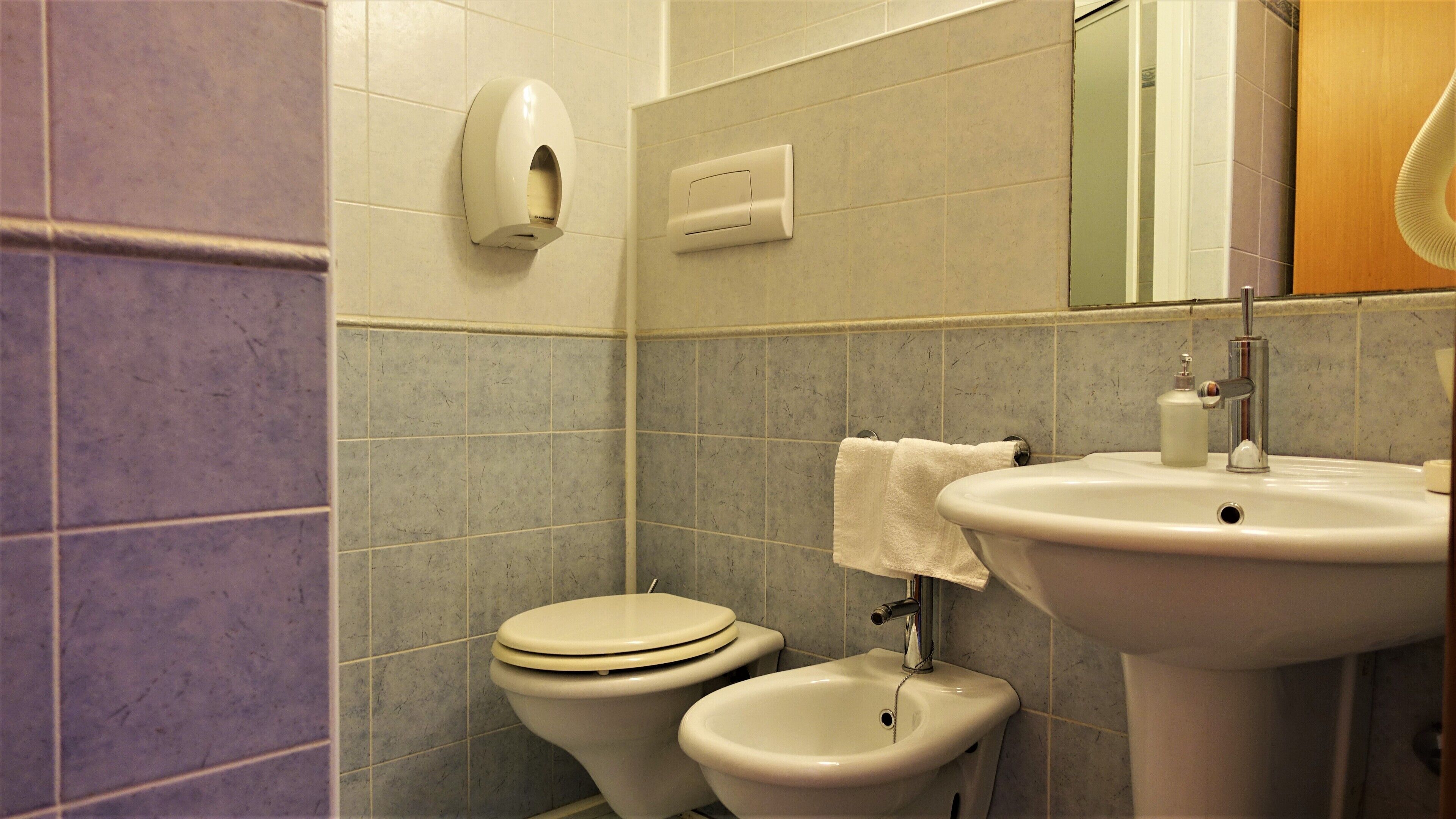 Baño con inodoro, bidé, lavabo y secador de manos.