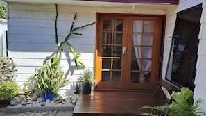 A wooden door with glass panels, a porch with potted plants, and a stone pathway leading to the door.