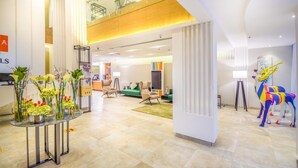 A modern hotel lobby with a reception desk, seating area, and a colorful sculpture. - Ewaa Express Hotel - AlRawda (Jeddah)