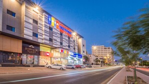 A hotel with multiple floors, a prominent sign for 'EWA EXPRESS HOTELS', and a visible 'ALE NOBLE 401' establishment across the street. - Ewaa Express Hotel - AlRawda (Jeddah)