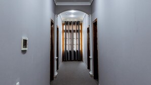 A hallway with grey walls, a carpeted floor, and doors on both sides leading to rooms. - Stella Hotel (Tashkent)
