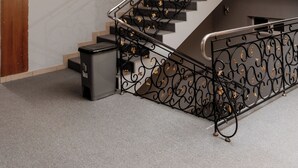 A staircase with ornate black railings, a wooden column, and a trash bin. - Stella Hotel (Tashkent)