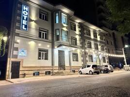 Un hotel con un cartel que indica 'HOTEL' y 'STELLA HOTEL' en la fachada, múltiples ventanas y un estacionamiento con coches.