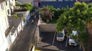 A residential street with houses, a parked car, and a person walking.
