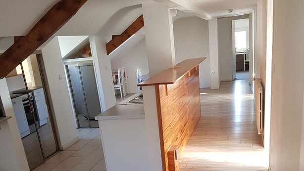 A spacious kitchen with modern appliances, a wooden dining area, and a view of the living room.