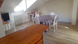 A dining area with a table and chairs, a radiator, and a television on a stand.