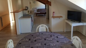 A compact living space with a kitchen, dining area, and a TV on a stand.