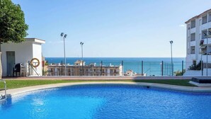 Una piscina amb vista al mar, envoltada d'edificis i una tanca.