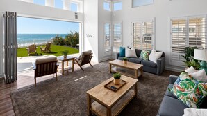 A spacious living room with a large sliding glass door leading to a balcony with a view of the ocean. - LOWER LEVEL Pet Friendly Oceanfront Condo P919-0 (Oceanside)