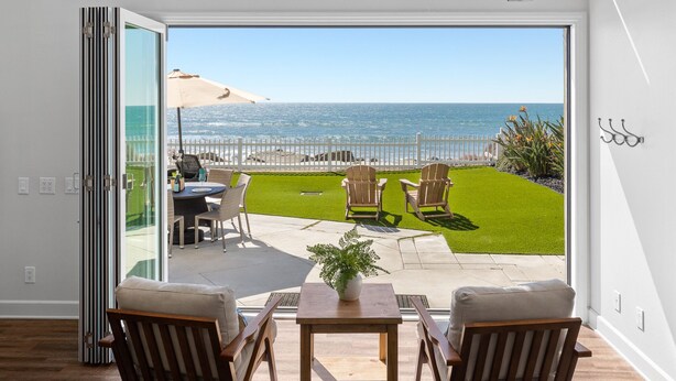 A modern living room with a large sliding glass door leading to a patio with a view of the ocean. - LOWER LEVEL Pet Friendly Oceanfront Condo P919-0 (Oceanside)