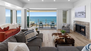 A modern living room with a large sliding glass door leading to a balcony with a view of the sea. - UPPER LEVEL Pet Friendly Oceanfront Condo P923-0 (Oceanside)