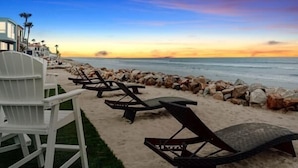 A beachside view with lounge chairs and a rocky shoreline. - UPPER LEVEL Pet Friendly Oceanfront Condo P923-0 (Oceanside)