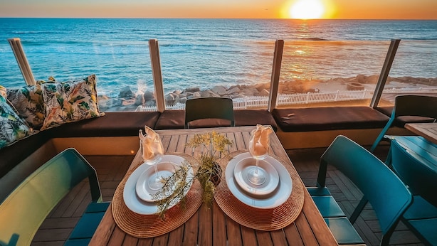 A table set for two with a view of the ocean at sunset. - UPPER LEVEL Pet Friendly Oceanfront Condo P923-0 (Oceanside)