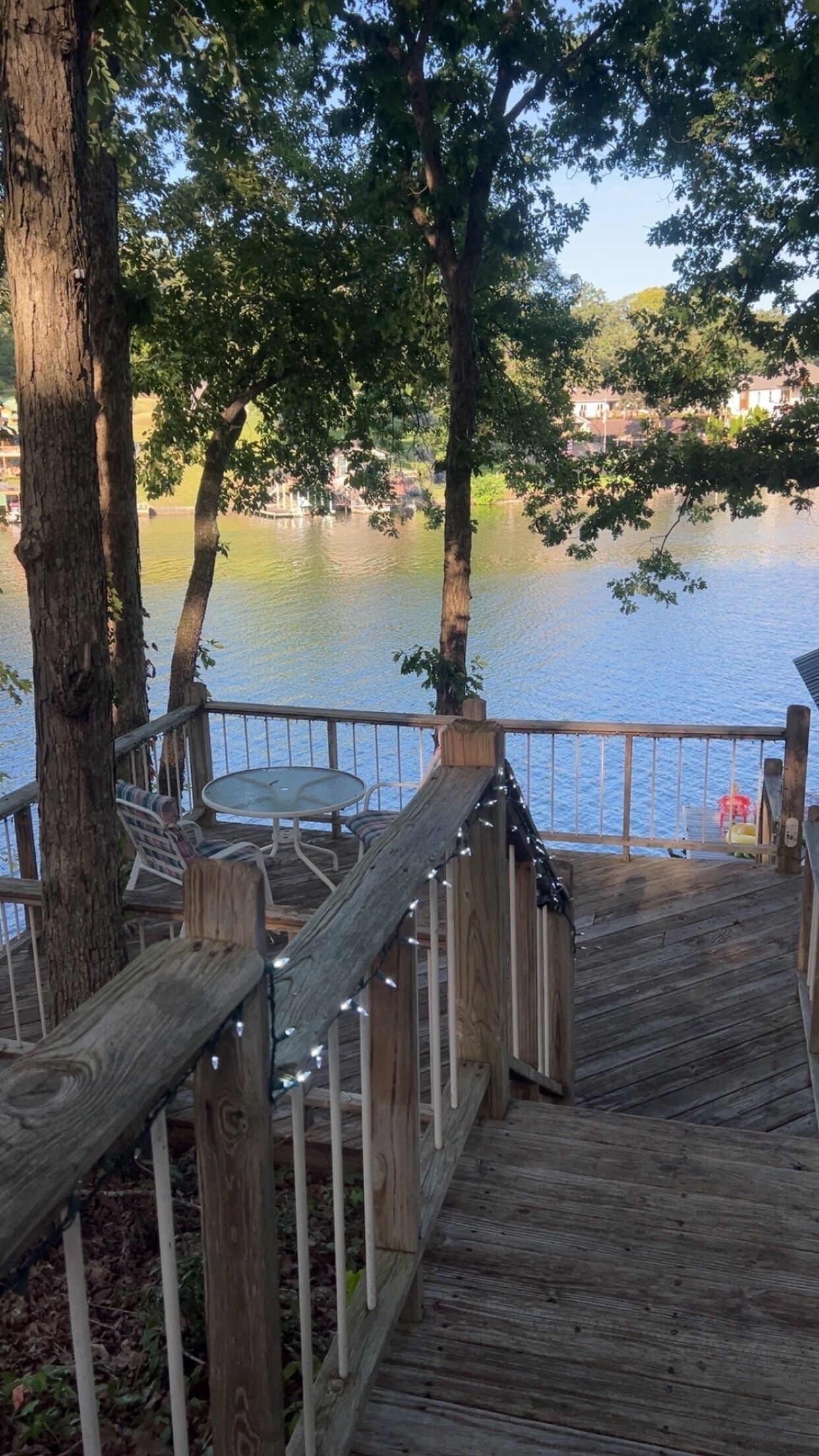 A wooden deck with a table and chairs, overlooking a body of water.