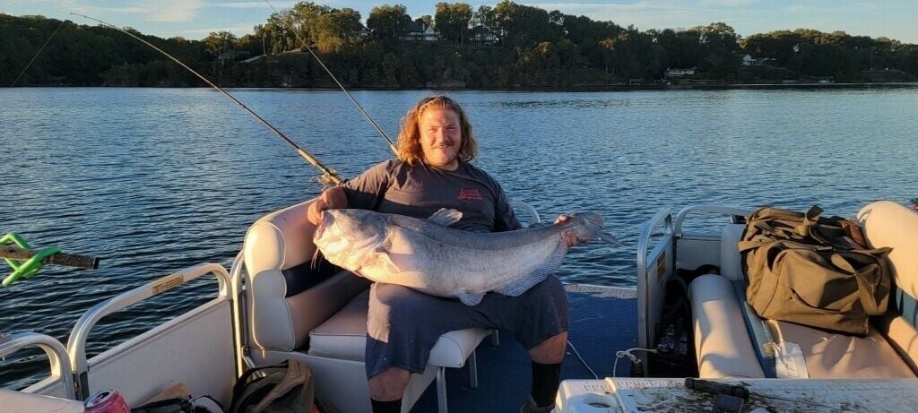 Une personne à bord d’un bateau tenant un gros poisson.