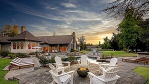 A patio with Adirondack chairs, a fire pit, and a pool.