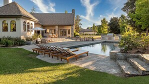 A house with a swimming pool, outdoor seating, and a well-maintained garden.