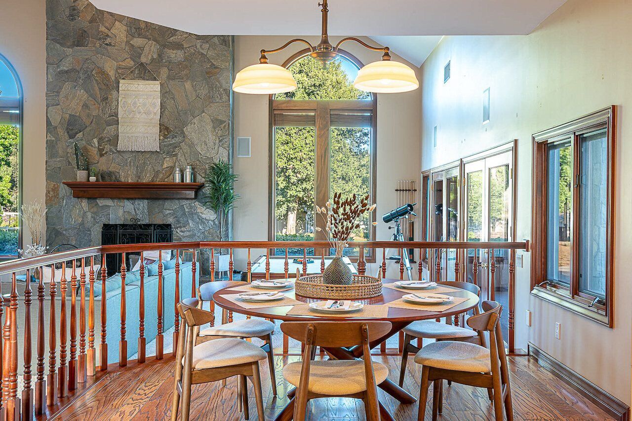 A dining area with a stone wall, wooden dining table, chairs, and a chandelier.