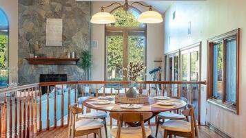 A dining area with a stone wall, wooden dining table, chairs, and a chandelier.