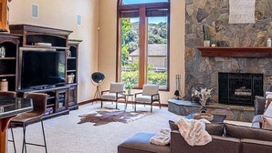 A spacious living room with a stone fireplace, a large TV, and a cozy seating area.