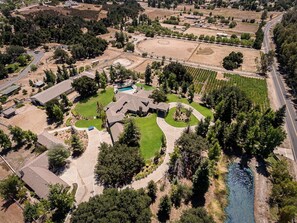 An aerial view of a residential area with houses, a swimming pool, and a river. - The Oaktree Estate by Fieldtrip - 7 Acre Private Resort with Pool & Vineyard (Murrieta)
