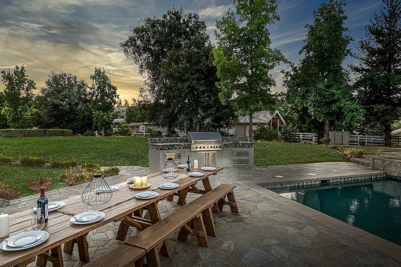 Ein Essbereich im Freien mit Pool, einer Steinterrasse und einer Grillstation.